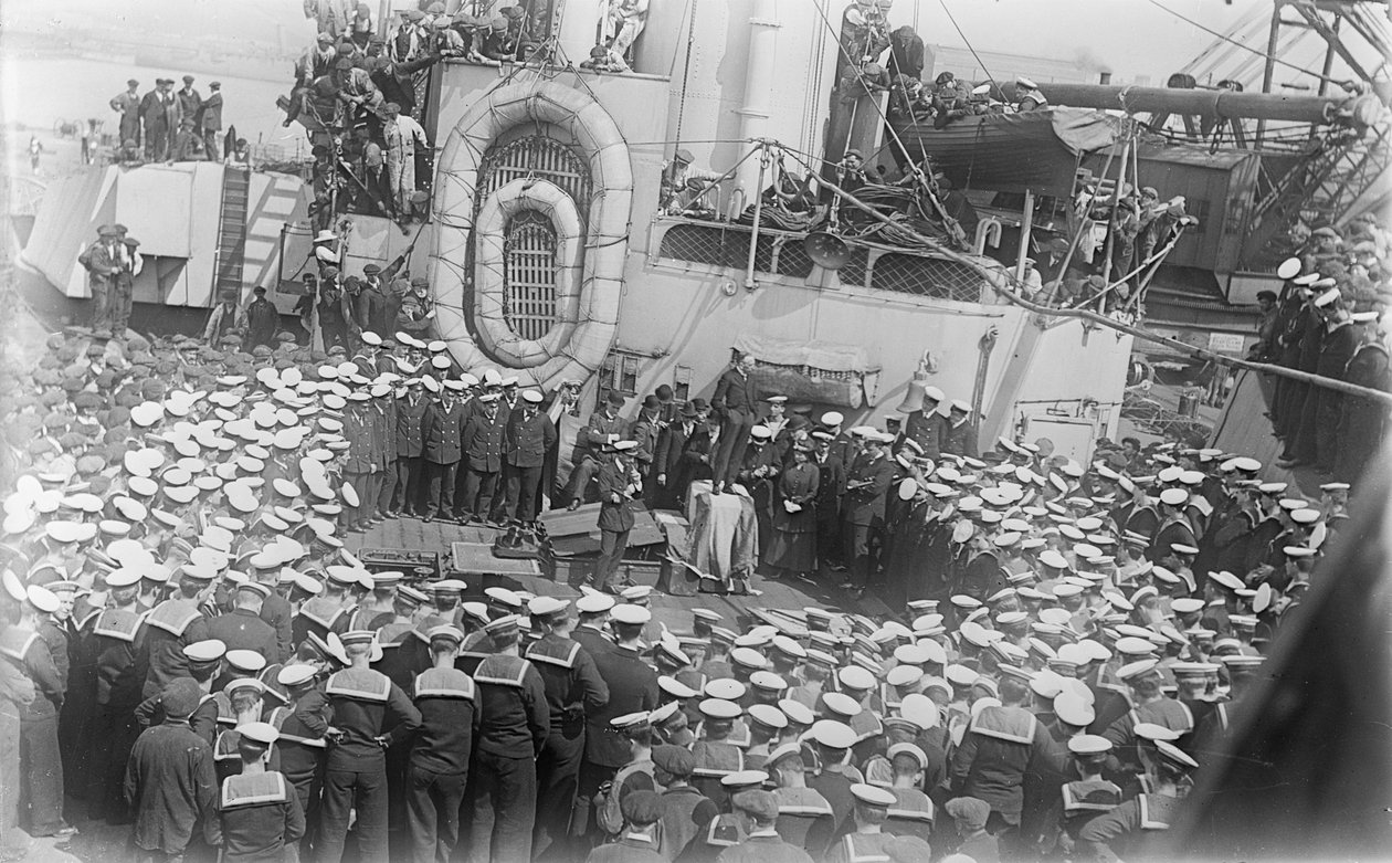 1916年5月21日、イギリスのデボンにある造船所のHMASオーストラリアのデッキで演説するオーストラリアの首相、ホン・ウィリアム・モリス（ビリー）ヒューズの周りに船員が群がる 作： オーストラリアの写真家