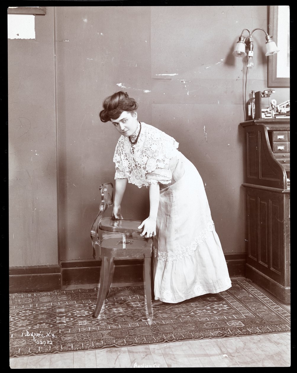 1906年または1907年にニューヨークのエオリアン社で特別な椅子を披露している女性（銀ゼラチンプリント） 作： バイロンカンパニー