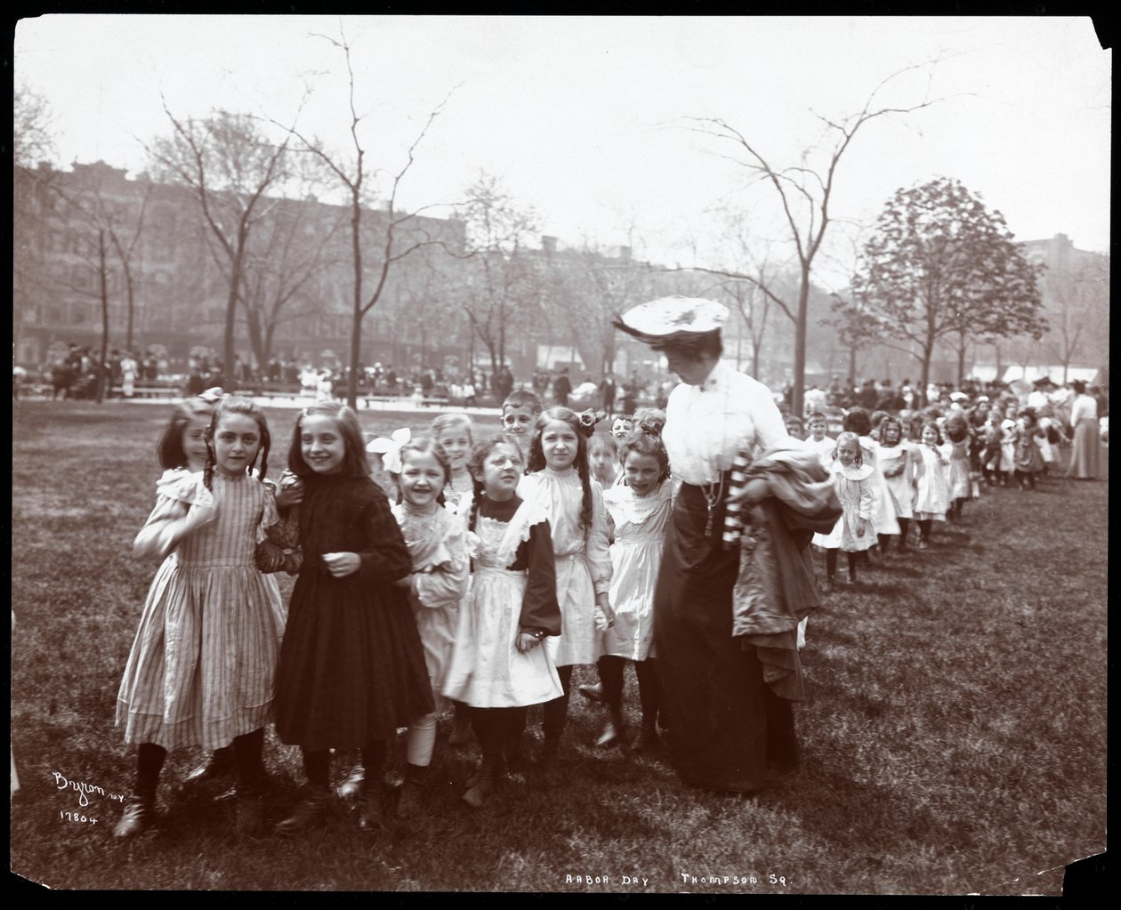 1904年ニューヨークのトンプキンススクエアパークでアーバーデーに女性に率いられている長い行列の子供たち（銀ゼラチンプリント） 作： バイロンカンパニー