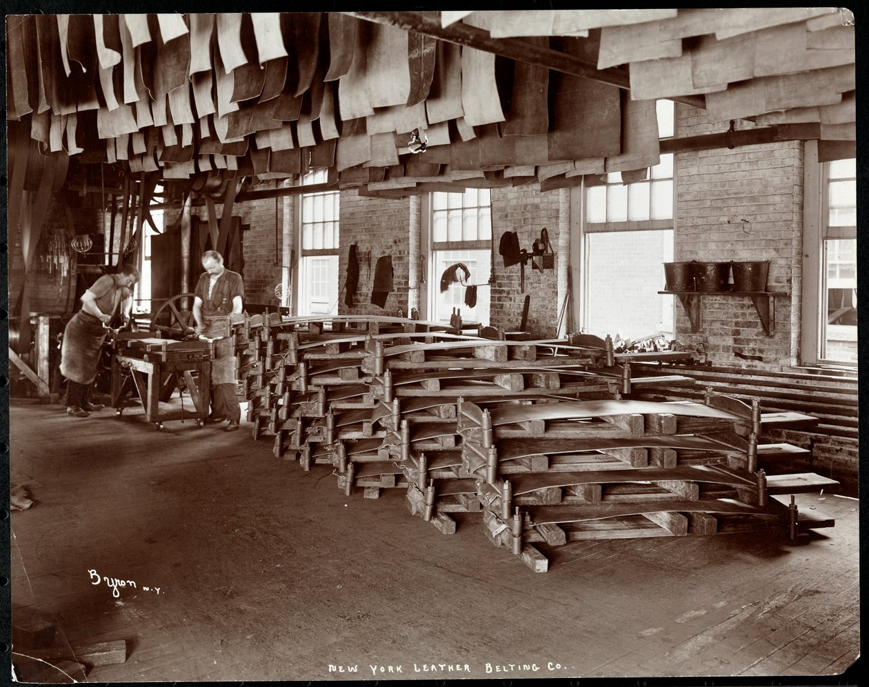 1905年、ニューヨークレザーベルト社で革を扱う2人の男性の内部ビュー（銀ゼラチンプリント） 作： バイロンカンパニー
