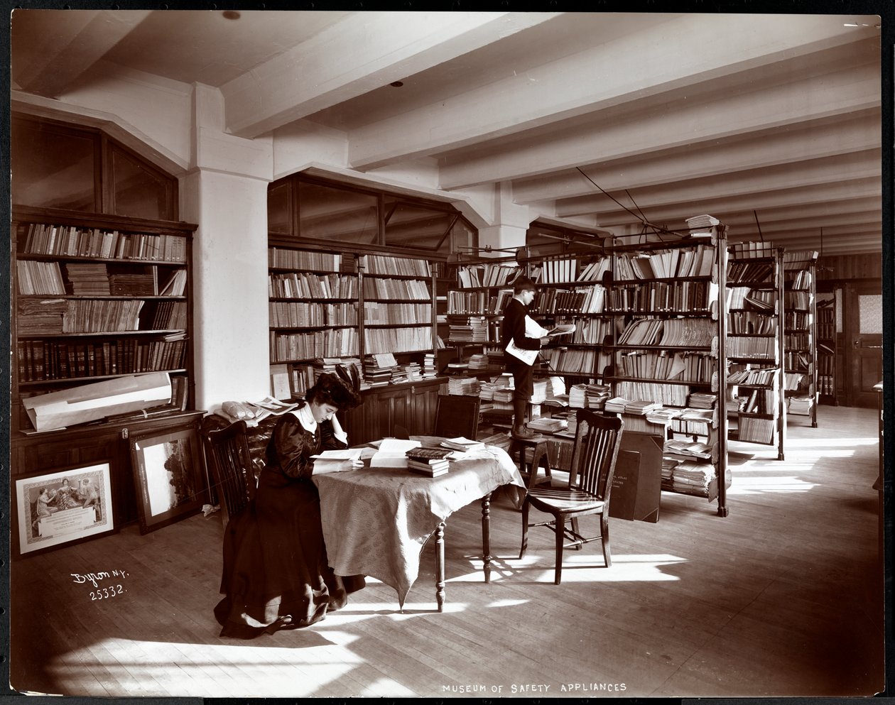 1907年にニューヨークのアメリカ社会福祉研究所の安全器具博物館の図書館にいる女性と若い男性（銀ゼラチンプリント） 作： バイロンカンパニー