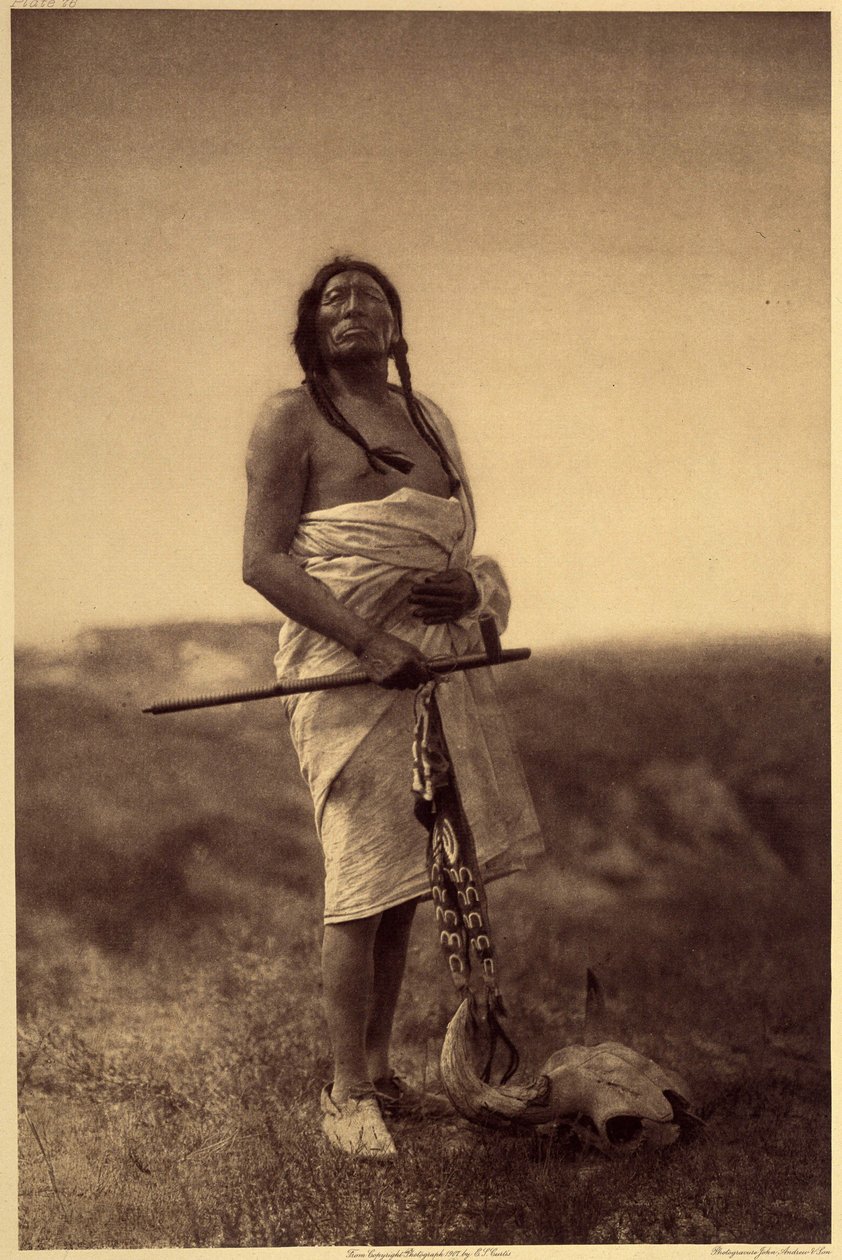 男性医師。 おそらく、手にはイカ、足には水牛の頭骨を持ったスー族だろう。 北米インディアンに関するエドワード S. カーティスの百科事典 (1868-1952) の第 3 巻から撮影された写真。セオドア ルーズベルトによる序文付き。 1907 年から 1930 年の間に、20 巻が出版されました。 作： エドワード保安官カーティス