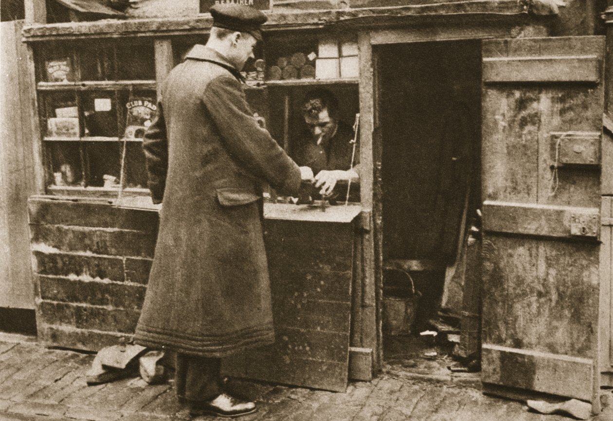 石畳のメイフェアミューズの間に合わせのブースで設立された靴屋は、1926-27に公開されたワンダフルロンドンの運転手からブーツを受け取ります（グラビア） 作： 英語の写真家