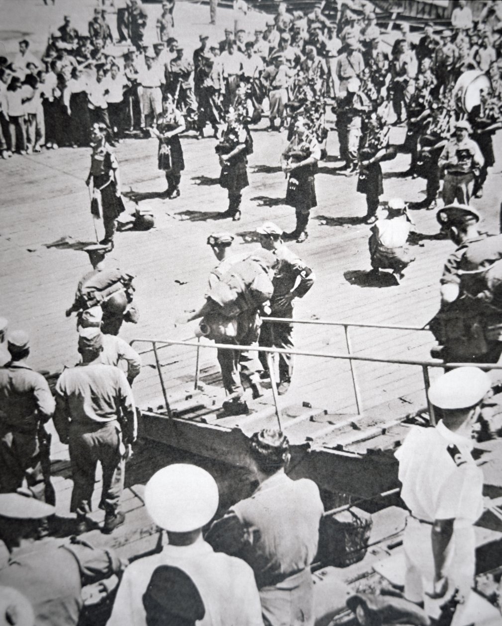 1950年8月29日、釜山のHMSセイロンからアーガイル・アンド・サザーランド・ハイランダーズ第1大隊に上陸したキルト・パイパーの演奏（モノクロ写真 作： 英語の写真家