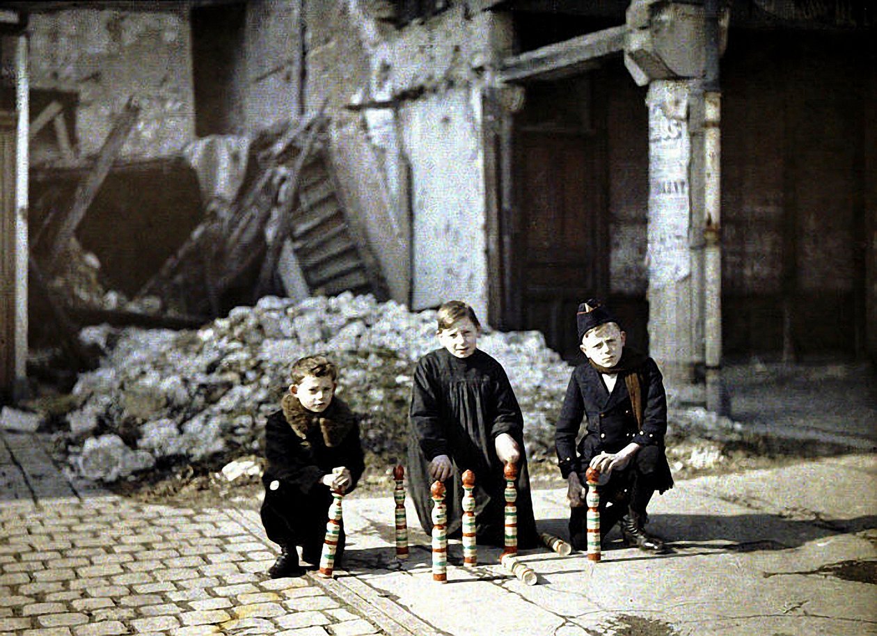 1917年にフランス、マルヌのランス、ドルーエデルロン広場でボウリングのピンで遊ぶ3人の子供（オートクローム） 作： フェルナンド・キュービル