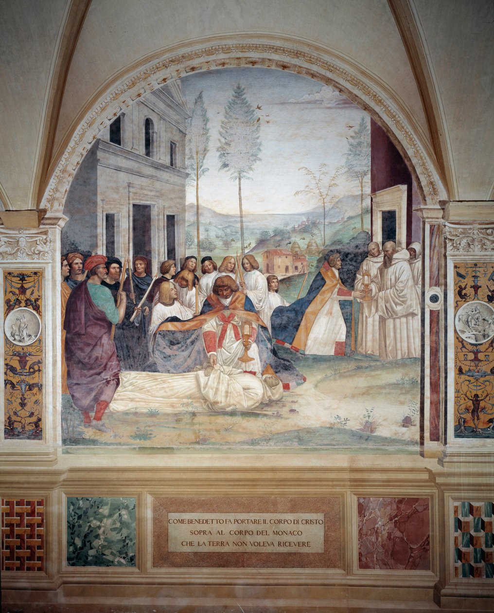 聖ベネディクトは、大地が埋葬を拒んだ修道士の体にキリストの体を乗せている アントニオ・バッツィ・ディット・イル・ソドマ（1477 - 1549）が作った回廊のフレスコ画で、ベネディ教団の創設者である聖ベネディクト・オブ・ヌルシー（480 - 567）の生涯を描いている。 作： ジョヴァンニ・アントニオ・バジ・ソドマ