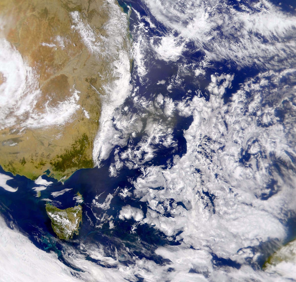 タスマン海の一部が雲に覆われた衛星写真。左側はオーストラリアの一部で、その下にタスマニアがあります。 NASA。理科 作： 全米航空宇宙局全米航空宇宙局