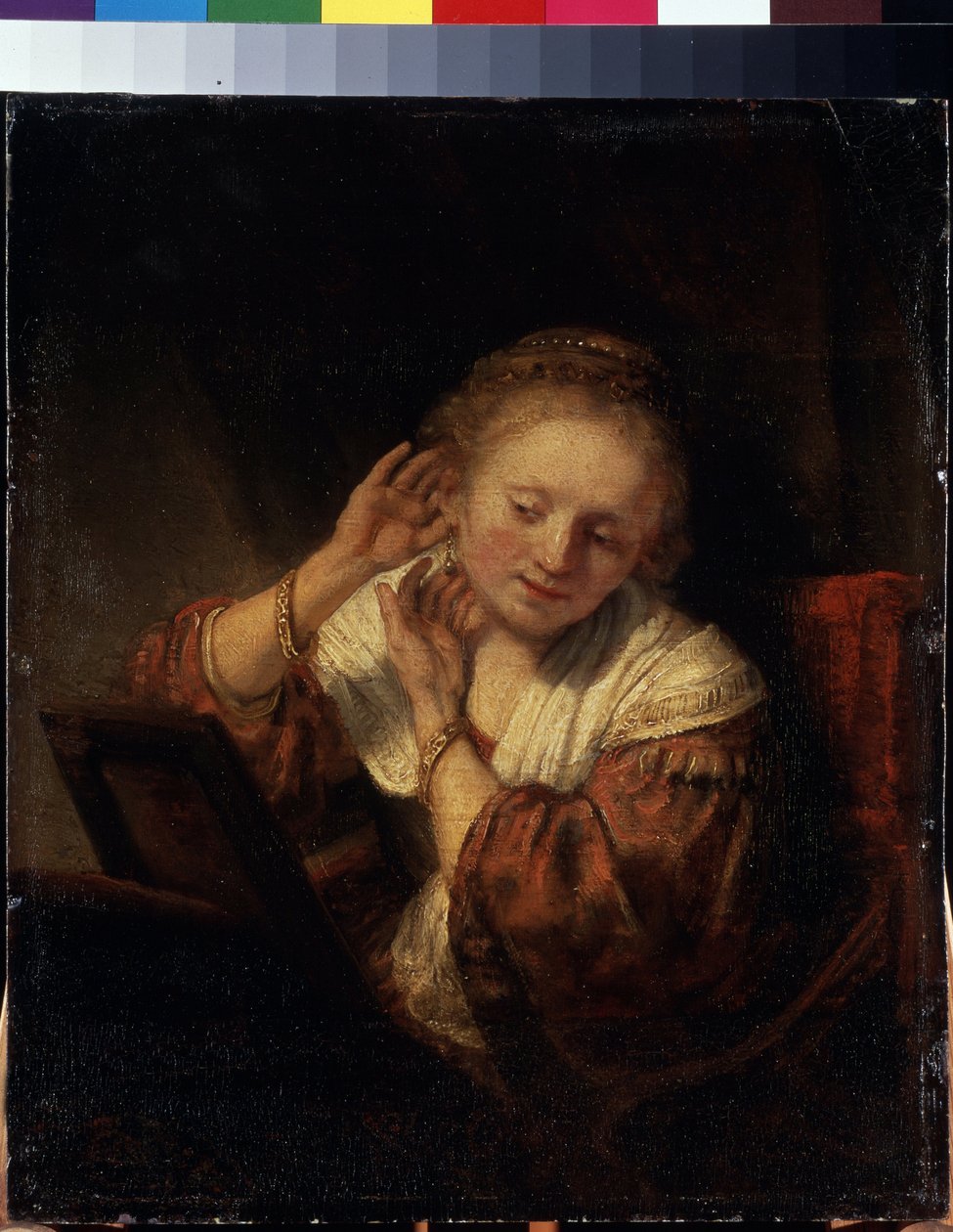 イヤリングを試着している若い女性。 イヤリングを試着している若い女性。 レンブラント (1606-1669) として知られる Harmenszoon van Rijn の絵画 作： レンブラント・ハルメンシュ。ファン・レイン