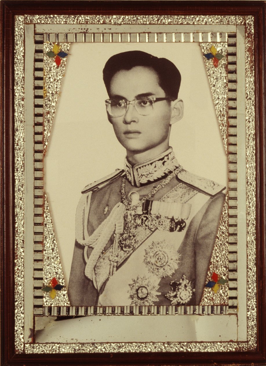 プミポン国王の肖像画（モノクロ写真）を額に入れて飾っています。 作： 不明