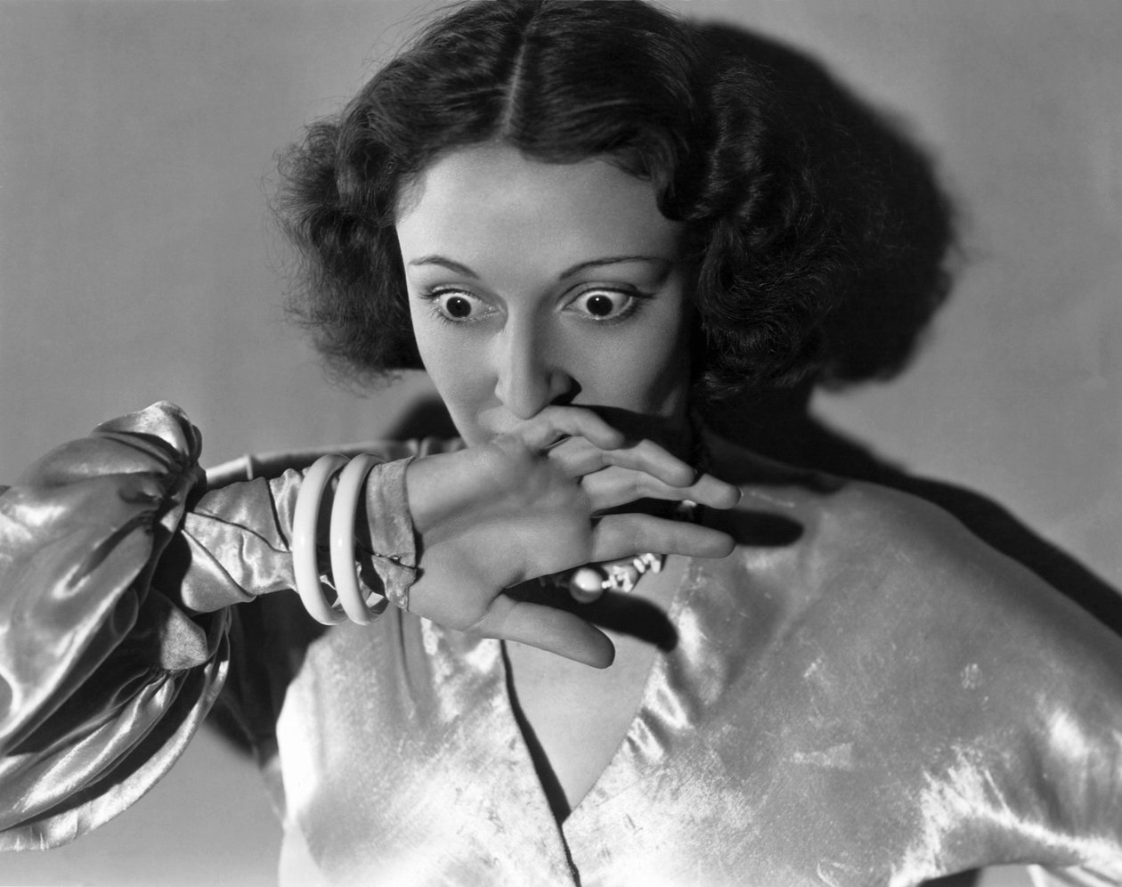 Hollywood, California: c.1932 怯えて口を覆う若い女性のクローズアップ。(白黒写真) 作： 不明