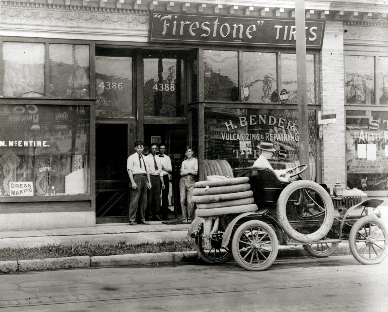 4388 Olive StreetにあるH. Bender Firestone Tireディーラーの外に集まった男性と自動車のタイヤ修理トラック 作： 不明
