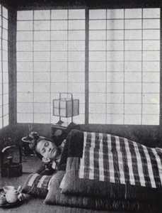 木製の枕を持って、わたがしのような布団の間で眠る少女（モノクロ写真 作： American Photographer (after)