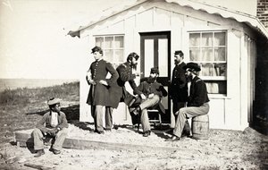 5人の南北戦争兵士が家の外のダートポーチに集まり、アフリカ系アメリカ人の若者が彼らの近くに座った、1861-65 作： American Photographer