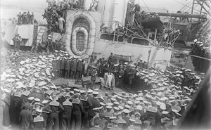 1916年5月21日、イギリスのデボンにある造船所のHMASオーストラリアのデッキで演説するオーストラリアの首相、ホン・ウィリアム・モリス（ビリー）ヒューズの周りに船員が群がる 作： Australian Photographer