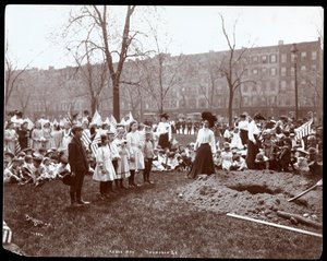 1904年にニューヨークのトンプキンススクエアパークで植樹の植樹のために新たに掘られた穴の周りに立っている旗を持っている大人と子供（銀ゼラチンプリント）