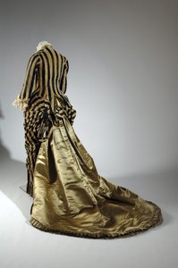 イブニング・ドレス、1884年頃（背面斜視図）。シルクサテン、カットベルベット、レース、シルク糸のタッセルとフリンジ。チャールズ・フレデリック・ワース、フランス。