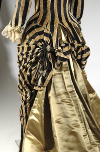 イブニング・ドレス、1884年頃（バッスルの詳細を示す後ろの斜視図）。シルクサテン、カットベルベット、レース、シルク糸のタッセルとフリンジ。チャールズ・フレデリック・ワース、フランス。