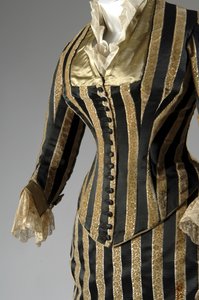 イブニング・ドレス、1884年頃（部分的に側面からの斜視図）。シルクサテンとカットベルベット、レース、絹糸のタッセルとフリンジ。チャールズ・フレデリック・ワース、フランス。