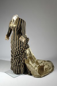 イブニング・ドレス、1884年頃（側面斜視図）。シルクサテンとカットベルベット、レース、シルク糸のタッセルとフリンジ。チャールズ・フレデリック・ワース、フランス。