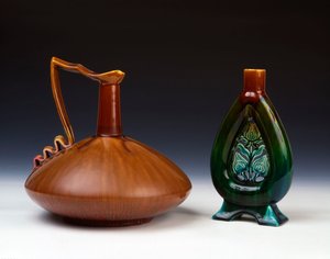 縞模様のキャラメル、緑と深紅の釉薬を備えた圧縮された球形のリンソープ陶器の水差しと、ピアスの花のつぼみの装飾とまだらにされた緑、青、茶色の釉薬を備えたリンソープ陶器の花瓶 作： Christopher Dresser
