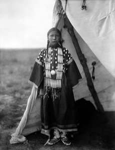 ローザ・ラメ・ドッグ、ティピの戸口に立つダコタ族の女性、c. 1905年、写真エドワード・S・カーティス 作： Edward Sheriff Curtis
