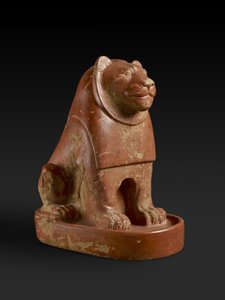 エジプトのヒエラコンポリスの寺院の境内にある、台座に座っているライオンの像。原始末期、旧王国の終わり、紀元前2700〜2200年頃（陶器）