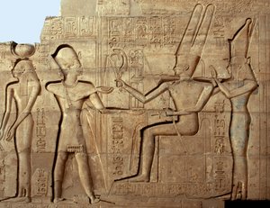 エジプトの古代遺物：ファラオ・ラムセス2世がテバン族の三神（アモンとムート）の前にいる様子を描いたレリーフ：ファラオ・ラムセス2世（紀元前1279～1213年）に捧げられた葬祭殿（エジプト・ルクソールのラマッセウム跡）。 作： Egyptian 19th Dynasty