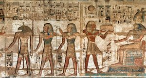 エジプトの古代遺物：第一の中庭、神人ホルスとクヌムへの供物を運ぶファラオを描いた彩色レリーフの詳細。ラムセス3世（紀元前1187〜1156年）の葬祭殿。エジプト、ルクソール、メディネト・ハブー
