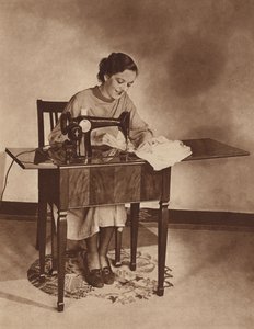 ミシンで仕事をする主婦、1930年代半ば（モノクロ写真） 作： English Photographer