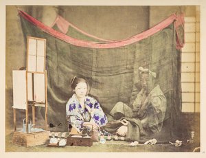 余暇を楽しむ日本人夫婦、 若い日本人女性のアトリエのタブローには、お茶を淹れる障害物が彼女の周りに座っており、彼女の後ろに座っている男性像にパイプを渡し、リネンの蚊帳で保護されています。   撮影者：不明  ルーカス コレクション: 作： English Photographer