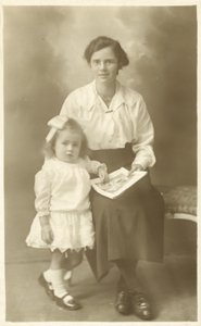幼い子供に写真を見せている母親か家庭教師のような可愛い女の子（モノクロ写真） 作： English Photographer
