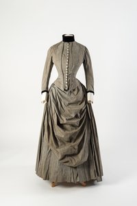 グレーのコットンドレス、ドレープの入ったエプロンフロント、襟とカフスに黒のベルベットのトリミング、1880年代後半（コットン 作： English School
