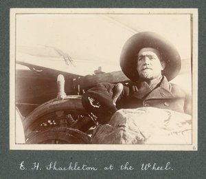 ディスカバリー号」の車輪のそばに立つE・H・シャクルトン（1901年） アーネスト・ヘンリー・シャクルトン卿のアルバム「National Antarctic Expedition（1901-1903）」より。 作： アーネスト・ヘンリー・シャクルトン