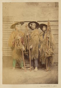[草の衣をまとい、つばの広い帽子をかぶった3人の日本人男性]