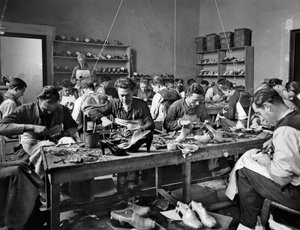 1937年にフィレンツェのパラッツォフェローニにある靴のデザイナー兼製造者であるフェラガモのスタジオで職人が働いていた（ガラス板）