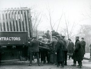1924年にロンドン動物園で飼育員がサイからトラックから荷降ろしされると、見物人の群衆が待機します。 作： Frederick William Bond