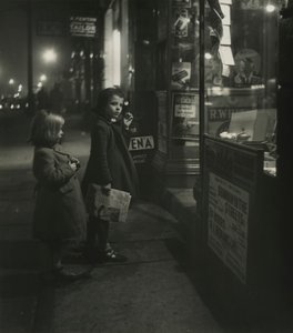 冬のコートを着た2人の少女が夜の店の外に立っている。 作： Godfrey Macdominic