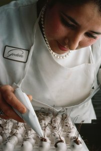 フォンダンショコラをかけたチェリーにチョコレートの茎をつけるゴディバのシェフ。ベルギー、ブリュッセル。 作： James L Stanfield