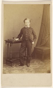 [本が置かれたテーブルに立つスーツ姿の少年] 作： Joseph Brown