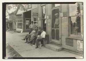 雑貨店の前のベンチに座る犬を連れた男たち 作： Lewis Wickes Hine