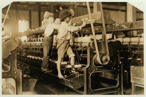 1909年、ジョージア州メイコンのビブミルで、壊れた糸を修理して空のボビンを交換するために、スピニングフレームに登る小さな男の子