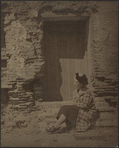 [老朽化したビルの前に座る女性］ 作： Louis Fleckenstein