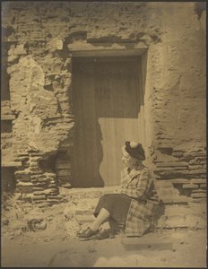 [老朽化したビルの前に座る女性］ 作： Louis Fleckenstein