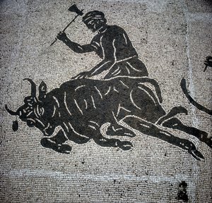 雄牛の屠殺シーンを描いたモザイクで、オスティア（Ostia）（ローマ近郊）で発見された。現在は旧オスティアの消防署に保存されている。 作： Roman Roman