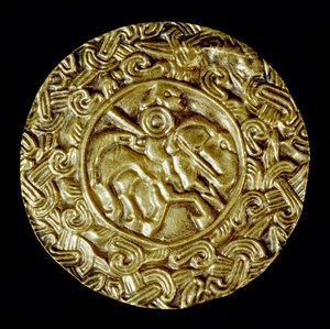 中世の考古学（Middle Ages）。ロンバルディア州の蛮族の芸術：金の円盤。中央には槍を持った馬上の聖人が、周囲には動物のモチーフが描かれています。ロンバルディア美術、600年頃。薄さ：47cm イタリア、チヴィダーレ・デル・フリウリ、考古学博物館 作： School Lombard