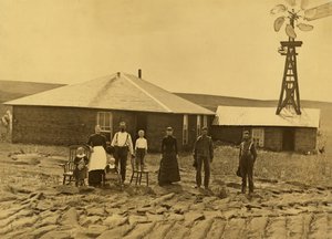 1885年頃、ネブラスカ州カスター郡、隣接する建物の屋根に風車が設置されたソッドハウスの外での農民一家（モノクロ写真）。