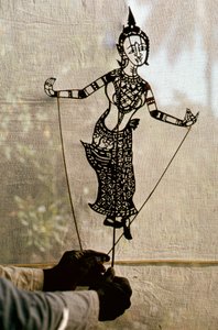 影絵芝居のためにスクリムに向かって紙芝居の影絵を操る人形遣い。C... 作： Thomas J. Abercrombie