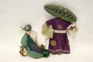 ミス・グリーンピースのボロ人形、頭はサヤエンドウの形をしており、ピンクのサテンのリボンでペットのアヒルをつないでいる。 作： Una Maw