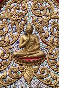 20151102、バンビエン、ラオス 。金のレリーフで装飾された入り口のドア。釈迦の生涯のある瞬間、すなわち釈迦が悟りを開いた後に行った最初の説教を描いた「教えの仏陀」。 作： Unbekannt