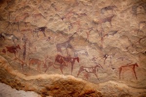 ロックアート、先史時代。スーダンのウワイナット山塊に描かれた、装飾されたシェルターの中にいる牛の群れと多色のキャラクター（羊飼いと弓矢）の岩絵。紀元前8000年から3000年の時代。写真撮影 作： Unbekannt